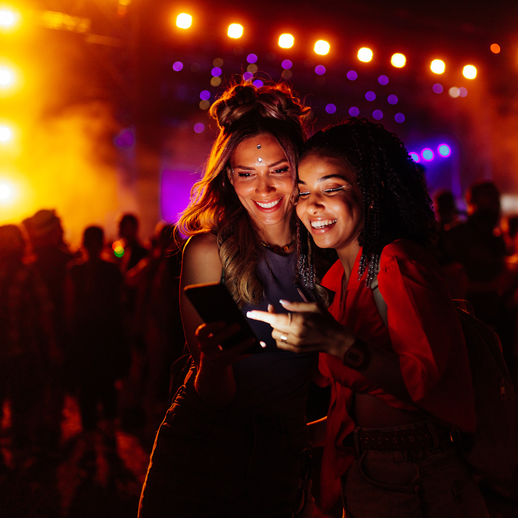 Female friends using cellphone at music festival